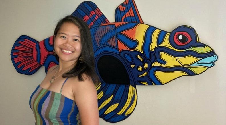 A woman stands in front a colorful display of a fish.