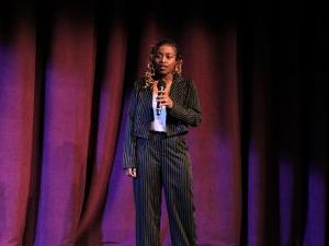 Photo of a woman speaking on a stage.